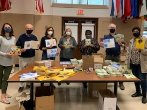 Masked MBR members hold up books for Head Start